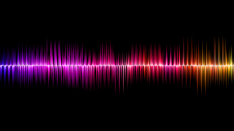 A colourful audio waveform visualisation displays frequency amplitude across a horizontal axis on a black background. The waveform transitions smoothly from blue and purple on the left to red, orange, and yellow on the right, highlighting variations in sound intensity and frequency.